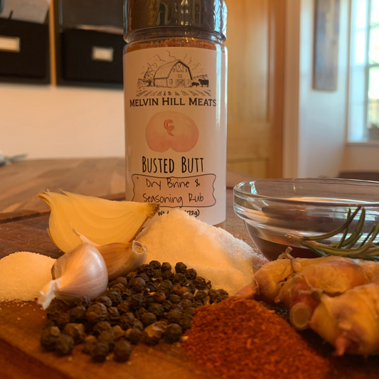 Busted Butt seasoning blend bottle with raw ingredients on cutting board.