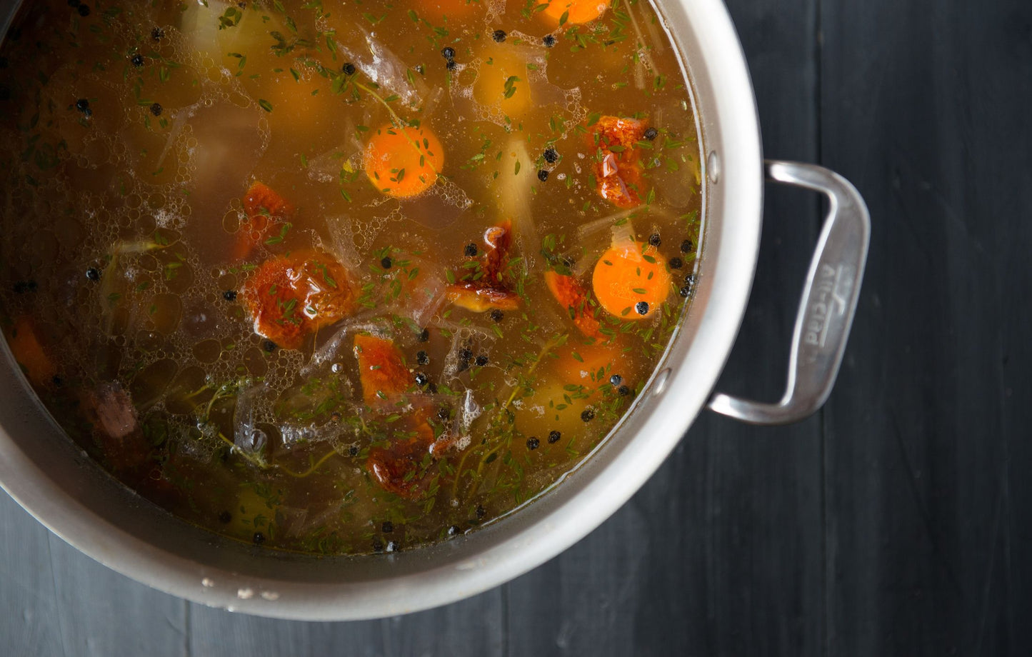 Beef bone broth in a pot with vegetables and seasonings.