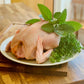 Whole pasture raised organic chicken on cutting board with fresh green herbs